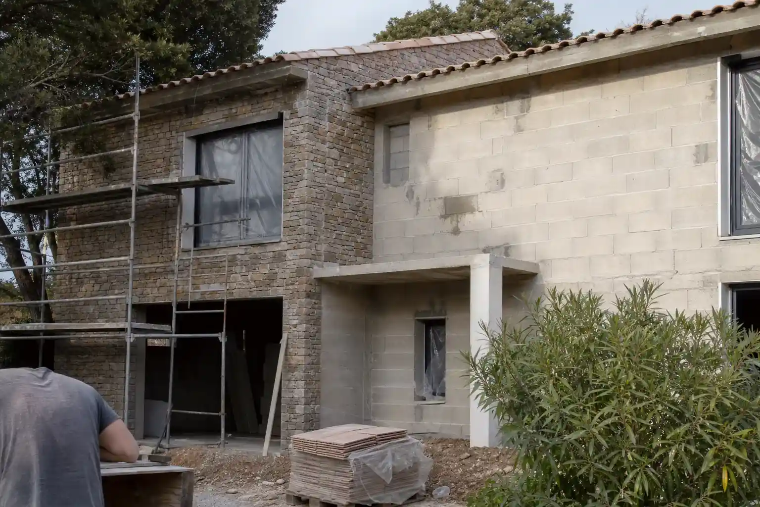 Maison individuelle en fin de chantier, échafaudage partiellement démonté et façade enduite déjà terminée