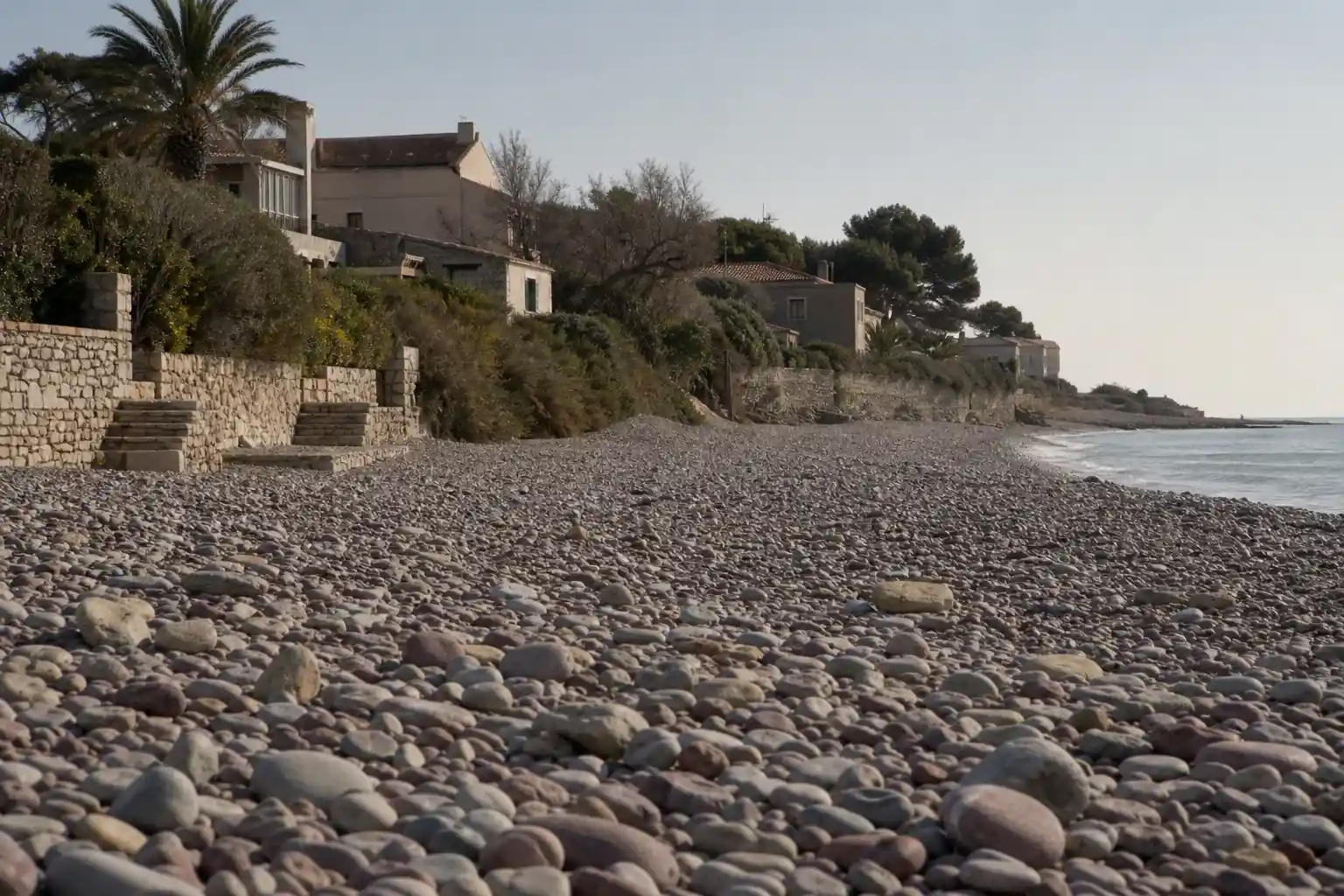 Front bâti en bord de Méditerranée sur la Côte d’Azur, maisons basses en surplomb d’une plage de galets