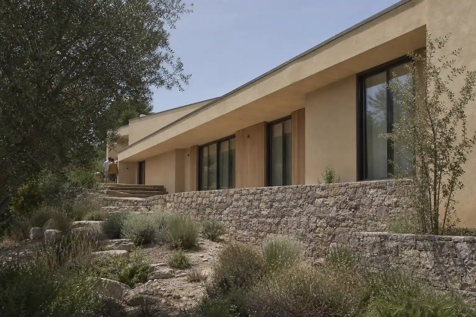 Villa contemporaine de plain-pied posée sur un terrain en pente, grande terrasse abritée par un débord de toiture